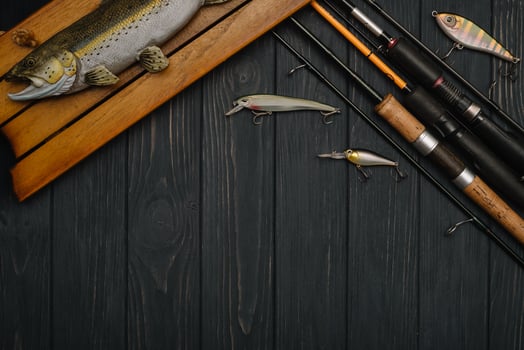 Fishing tackle - fishing spinning, hooks and lures on darken wooden background. Top view photo