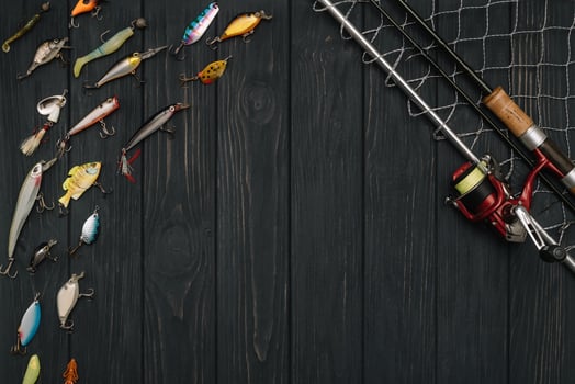 Fishing tackle - fishing spinning, hooks and lures on darken wooden background. Top view photo