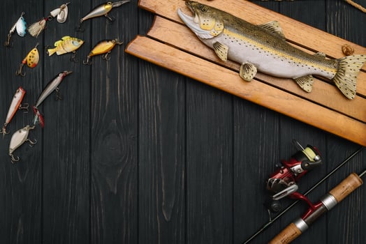 Fishing tackle - fishing spinning, hooks and lures on darken wooden background. Top view photo