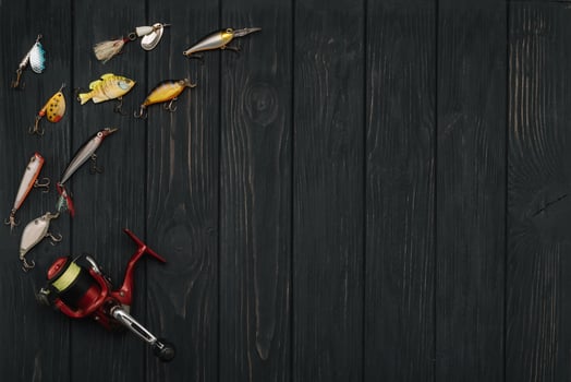 Fishing tackle - fishing spinning, hooks and lures on darken wooden background. Top view photo