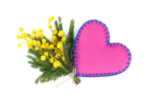 Heart shaped pillow next to yellow mimosa flowers photo
