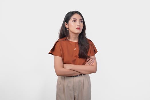 Beautiful young Asian woman in brown shirt making an annoyed expression with pouting lips on isolated white background. photo