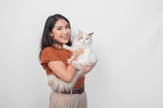 Portrait of young Asian woman in brown shirt holding her ragdoll cat and smiling to the camera isolated over white background. photo