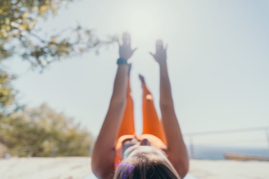 Fitness woman sea. Happy middle aged woman in orange sportswear exercises morning outdoors on yoga mat with laptop in park over ocean beach. Female fitness pilates yoga routine. Healthy lifestyle. photo