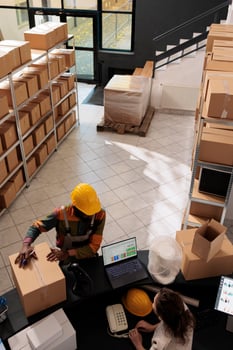 Diverse employees standing at counter desk in stockroom, preparing customer order for delivery. Storage room coworkers discussing merchandise quality control, working at inventory in warehouse photo