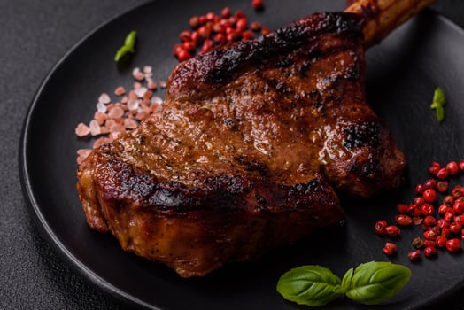 Delicious juicy beef steak on the bone, tomahawk with salt, spices and herbs photo