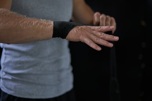 Anonymous kickboxer wrapping bandage on hand in gym photo
