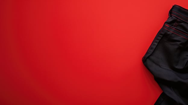 A striking red background with a corner of black jeans, offering a bold contrast photo