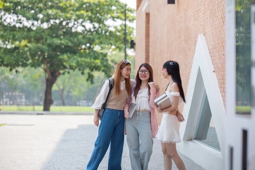 College friends walk to class together. University student in campus talk and have fun outdoors photo