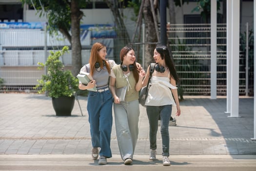 College friends walk to class together. University student in campus talk and have fun outdoors photo