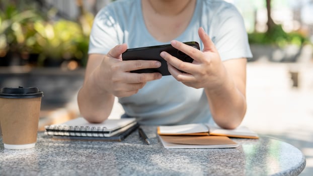 A woman using her smartphone, watching a while sitting at an outdoors table at a cafe. photo