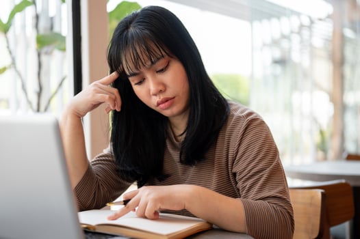 A serious and concentrated young Asian woman is reading a book in a cafe. photo