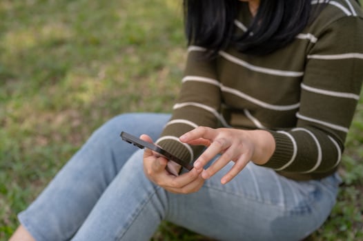 A woman is using her smartphone, chatting with her friends while relaxing in a park. photo