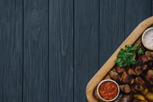Most meat dish - beef kebabs, sausages, grilled mushrooms, potatoes, tomatoes and sauce. The best choice for a beer. Close-up on a wooden background. photo