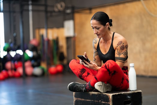 Sportive mature woman using phone on a cross training gym photo