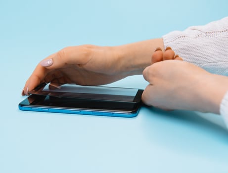 Smartphone with screen protect glass cover in hands. blue background. women hand stick tempered glass shield or film screen cover with mobile phone. protector concepts ideas photo