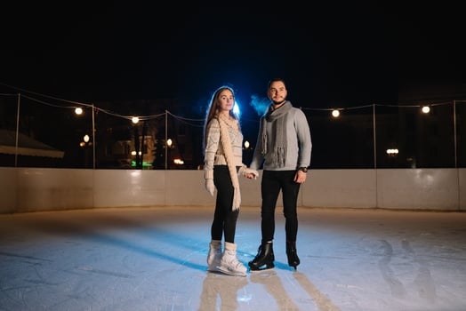 Winter skates, loving couple holding hands and rolling on rink. Illumination in background, night. Concept training. photo