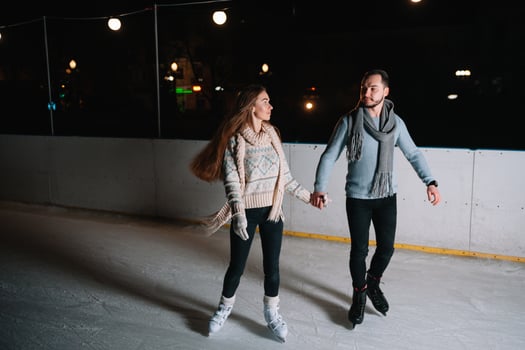 Winter skates, loving couple holding hands and rolling on rink. Illumination in background, night. Concept training. photo