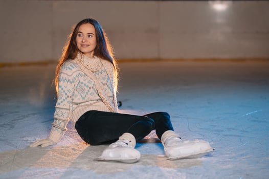 Portrait young smiling woman in white hat with skates on ice rink photo