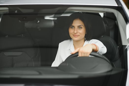 Photo of happy young woman sitting inside her new car. Concept for car rental