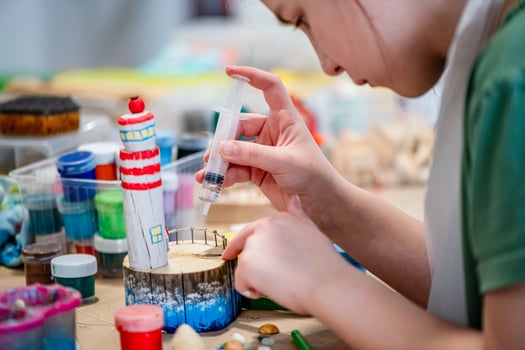 cute teen girl at a master class making a DIY wooden lighthouse made of wood, exhibition of crafts, crafts fair, education, master classes photo