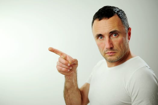 Adult unshaven handsome man shows his finger Turn your face sideways into the frame billboard banner Open wide blue eyes white background studio Advertising space for text photo