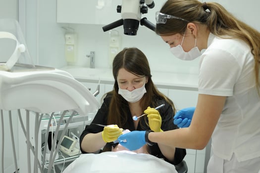 dentist doctor and nurse treat teeth to a patient using a microscope Female patient opening her mouth under the dental microscope and a professional dentist holding tools photo