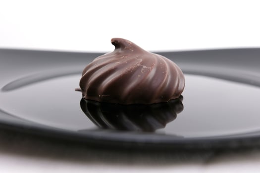 Melted chocolate is poured on a chocolate sweet and delicious chocolate covered marshmallow on a wooden table. 4K. photo