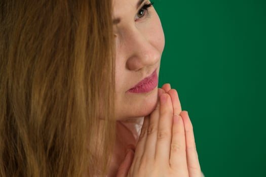 Cute and fresh dreamy girl with both hands together looking at the side. green background. photo