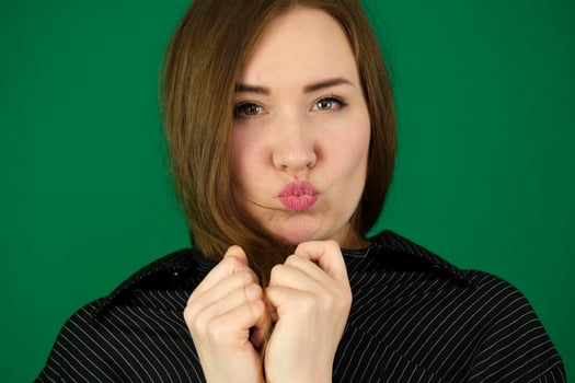 beautiful girl blow kisses woman on a green background chromakey in a black striped mens shirt different emotions facial expression close-up advertising space for text clean. kind eyes photo