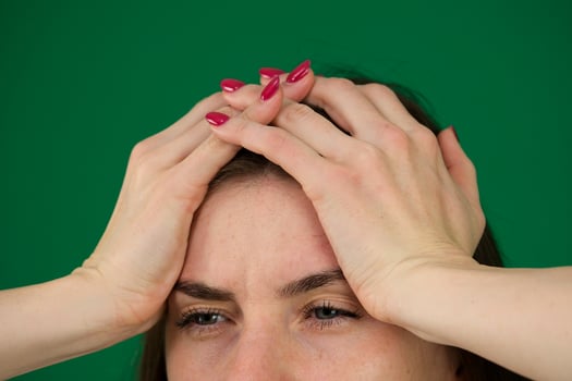 A young woman with a headache holding head, isolated body parts of a young woman on a green background chromakey photo