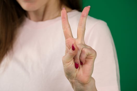 Female hand with manicure showing two fingers shot closeup body parts of a young woman on a green background chromakey photo