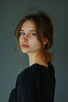 A beautiful young woman with long brown hair and green eyes is looking over her shoulder at the camera. She is wearing a black t-shirt and has a soft smile on her face. photo
