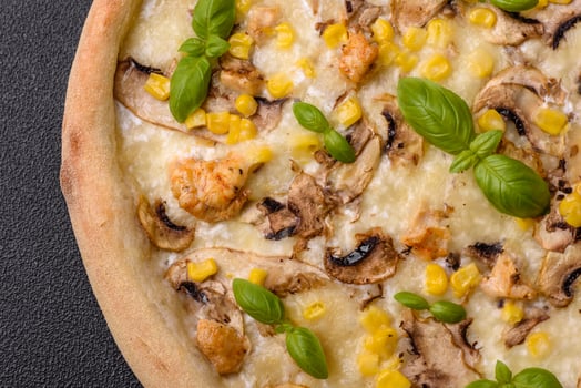 Delicious pizza with corn, cheese, tomatoes and mushrooms, salt, spices and herbs photo