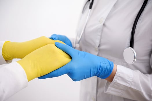 blue and yellow gloves flag of Ukraine aid to refugees medical care in medical institutions war in Ukraine Doctor's hands in gloves holding man's hands. Medical with copy space. Care concept. photo