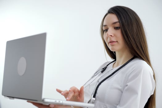 Young female doctor looking away while using laptop at desk in clinic photo