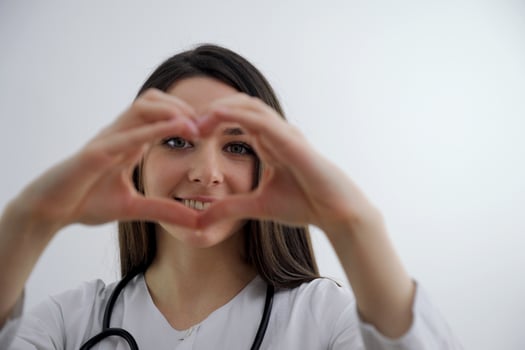 Cute Little Indian girl doctor examining Stuffed heart toy with stethoscope while wearing Doctor's uniform. Standing isolated over white background photo