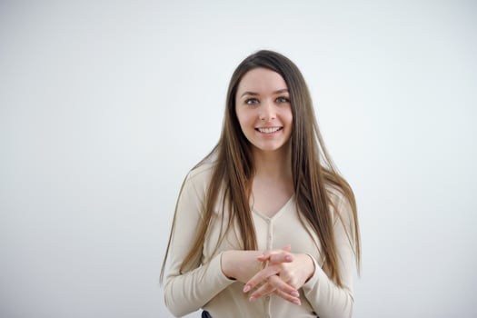 a young girl crossed her fingers on her chest listens attentively smiles wants to like something pleasant The interlocutor look into the frame sweet smile long hair Ukrainian European beautiful photo