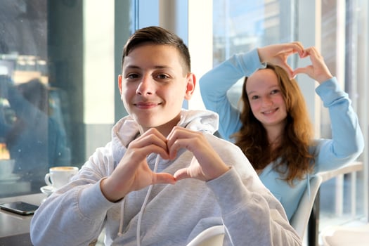 ad offers like show approval boys girl teenagers make heart with hands sit near window look into frame smile people, love and friendship happy smiling pretty teen girl and boy showing heart sing photo
