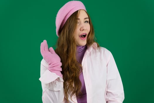 Smiling happy woman pointing at the camera with both hands and her head tilted to the side with a playful expression and focus to her face over grey photo
