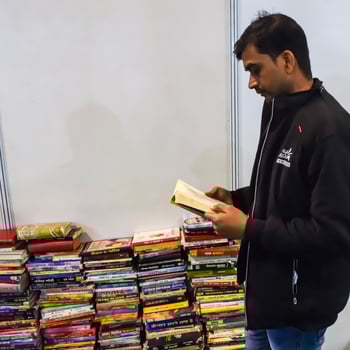 Delhi, India, February 17 2024 - Various age group people reading variety of Books on shelf inside a book-stall at Delhi International Book Fair, Books in Annual Book Fair at Bharat Mandapam complex photo