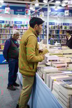 Delhi, India, February 17 2024 - Various age group people reading variety of Books on shelf inside a book-stall at Delhi International Book Fair, Books in Annual Book Fair at Bharat Mandapam complex photo