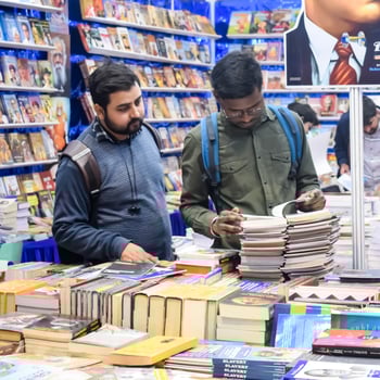 Delhi, India, February 17 2024 - Various age group people reading variety of Books on shelf inside a book-stall at Delhi International Book Fair, Books in Annual Book Fair at Bharat Mandapam complex photo