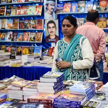 Delhi, India, February 17 2024 - Various age group people reading variety of Books on shelf inside a book-stall at Delhi International Book Fair, Books in Annual Book Fair at Bharat Mandapam complex photo
