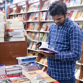 Delhi, India, February 17 2024 - Various age group people reading variety of Books on shelf inside a book-stall at Delhi International Book Fair, Books in Annual Book Fair at Bharat Mandapam complex photo
