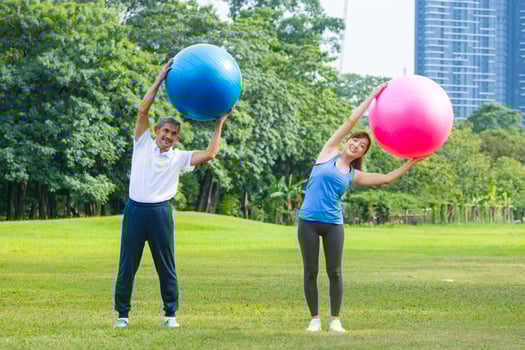Senior asian man and his daughter are exercising with yoga ball in public park to build core body muscle for elder longevity exercise and outdoor workout photo