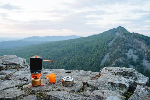 Breakfast of a tourist on a mountain slope, a set of dishes for cooking in nature on a hike. Orange tea mug. photo