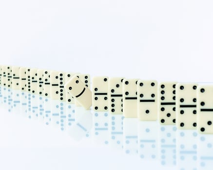Domino piece stopping domino effect on white background. photo