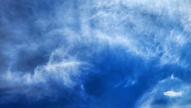 a blue sky with clouds and a plane flying in it photo
