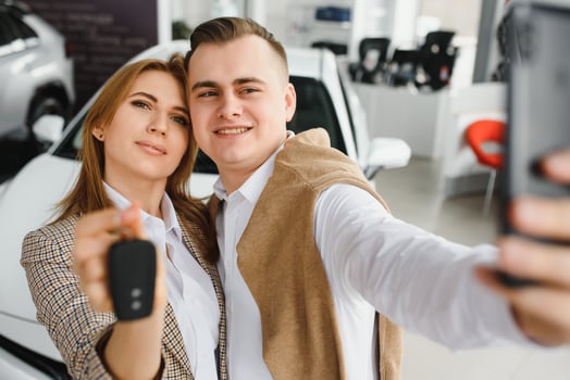 Family selfie in dealership. Happy young couple chooses and buying a new car for the family photo